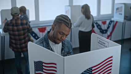 African American man comes to vote in booth in polling station office. National Election Day in the...