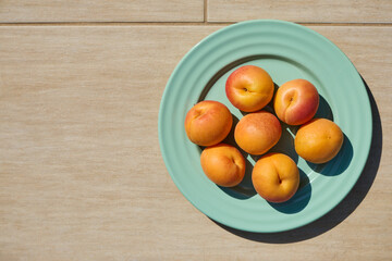 Fresh apricots on turquoise plate with beige background