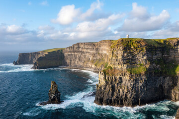 Aerial vast view of the Cliffs of Moher from the sea, featuring turquoise blue ocean and vivid blue...