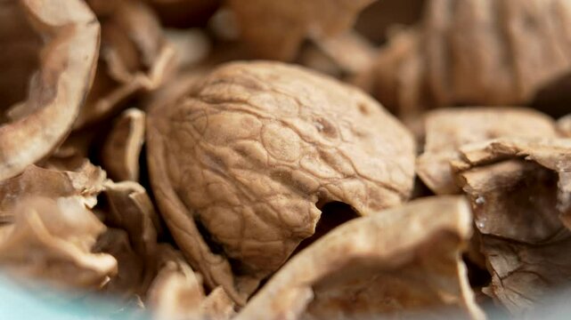 Broken crushed cracked organic empty walnut shells as leftovers and kitchen waste after eating in a glass bowl. Macro shot. Rotation. Healthy food concept
