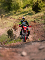 Obraz premium Professional enduro bike rider on action, dirt ride on the muddy road. Motocross sport.