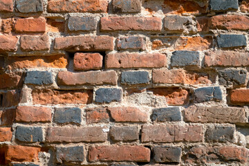 Fragment of a brick wall of the ancient medieval castle Ragnit. Destroyed bricks and black burnt ends are visible. Background. Texture.