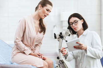 woman doctor look microscope at gynecologist's appointment. Female gynecologist examining patient...