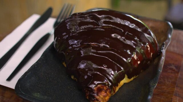 Chocolate croissant on gray plate in panning motion view.