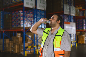 Time of rest from work. Tired warehouse employees man drinking water and resting after working at warehouse factory workplace.