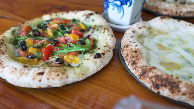 Pizzas on plates on wooden table with various flavouring.
