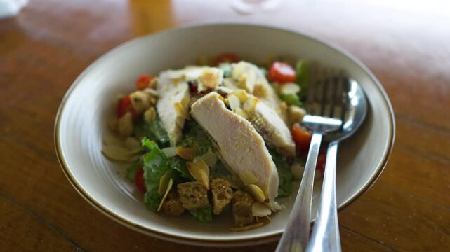 Panning moton around plate of chicken salad on wooden table.