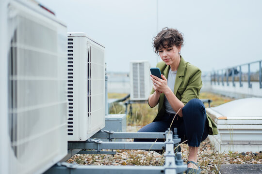 Businesswoman using smart phone by HVAC system
