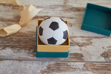 Soccer ball in jewelry gift wrapping on the table, a gift for a soccer fan, the beginning of the...