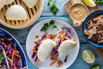 A serving of pulled pork stuffed and steamed bao buns, ready for eating.