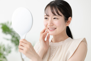 鏡を見て肌の調子を確認する女性