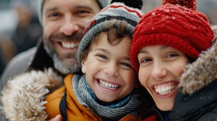 Obraz premium A cheerful family dressed in winter clothing, smiles brightly with snowflakes gently falling around them. The scene evokes warmth and joy amidst the cold weather.