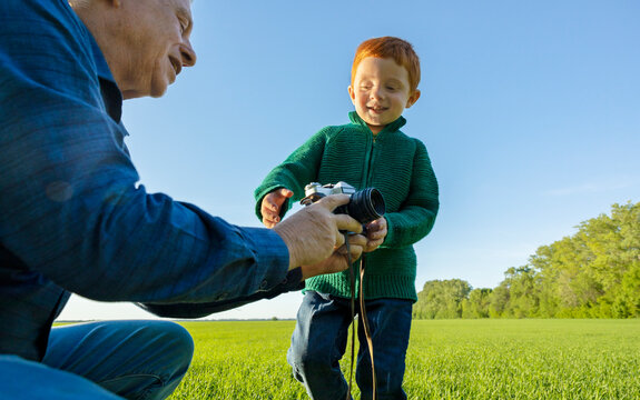 Grandfather gives old camera to his grandson in field