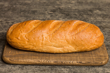 Freshly baked bread on cutting board against white wooden background. perspective view bread with copy space