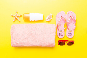 Summer holiday concept. Top view of beach towel, flip flop and sunscreen cream on table Top view...
