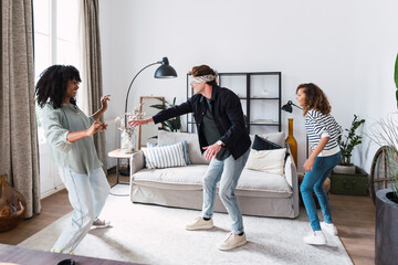 Happy parents playing blind man's buff with their daughter in the living room