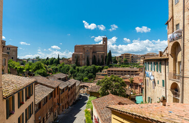 Siena, Italy - June 01, 2024: The San Domenico church and residential buildings. Sunny day, clear sky.