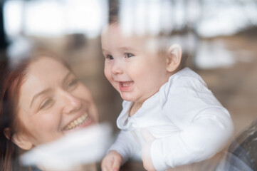 View through the window of a red-haired Caucasian woman holding her little son. 