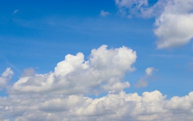 Obraz premium The puffy white clouds in the bright blue sky.