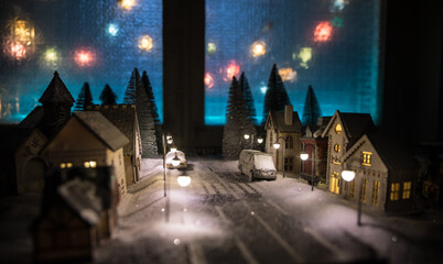 Little decorative cute small houses in snow at night in winter, Christmas and New Year miniature house in the snow at night with fir tree. Holiday concept.