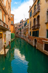 Venice, Italy - June 03, 2024: View to a colorful narrow calm canal from a bridge. Sunny day, clear sky.