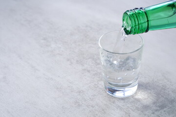 韓国の伝統的な蒸留酒、よく冷えた韓国焼酎（ソジュ）をグラスに注ぐ