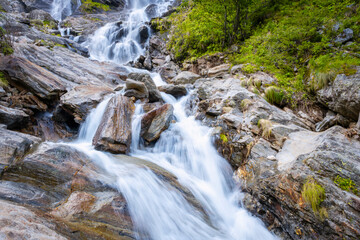 Obraz premium Mountain waterfall dropping from the peaks of Northern Italy Alps (Monte Rosa Massif, the 2nd highest mountain of Europe), during early summer.