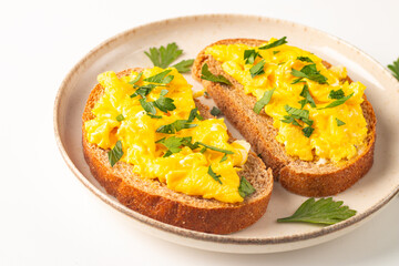 Scrambled eggs with green herbs on wheat-rye crispy toast.