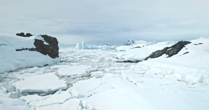 Drone flight over snow covered Arctic landscape. Frozen ocean coastline bay with melting ice. Beautiful South Pole winter wild nature. Antarctica travel and exploration. Global warming, climate change