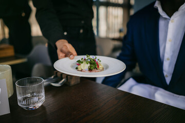 Waiter serving a fancy plate of food in a restaurant