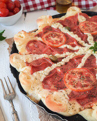 pizza sabor calabresa com catupiry, orégano, tomate, azeitona e borda vulcão na mesa com pimenta e garfo