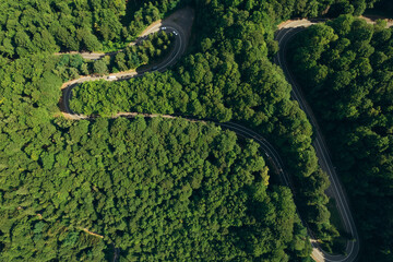 Aerial view of the road passing through the mountain and green forest. Curve asphalt road on mountain.