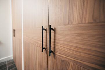 Close-up of wooden closet door with black handles