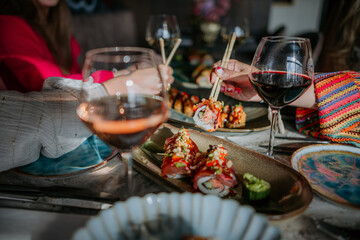 Close up shot of multiple sushi plates with people using chopsticks and wine
