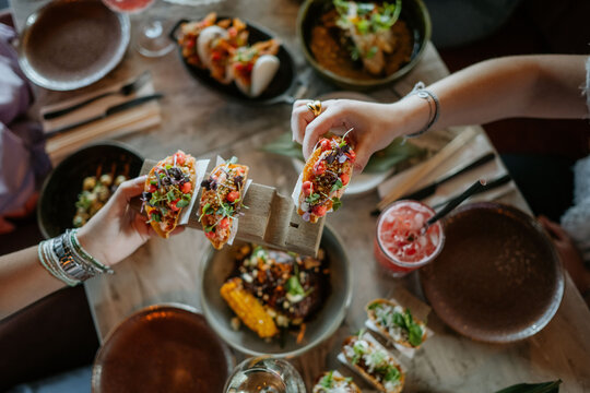 Person grabbing a fancy taco from a wooden plate in a fancy restaurant