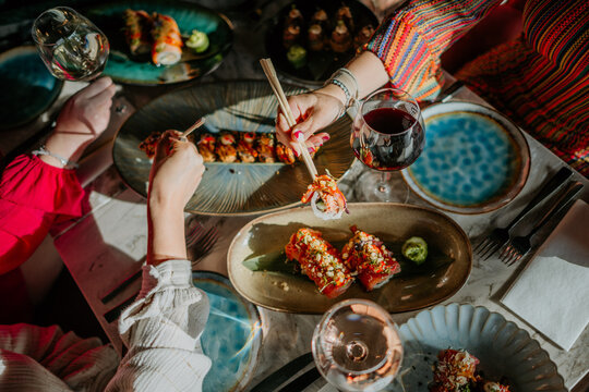 Close-up of people eating sushi with chopsticks in a restaurant