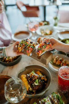 Person grabbing a fancy taco from a wooden plate in a fancy restaurant
