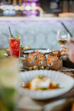 Closeup of taco's on a filled fancy restaurant table with cocktail and wine