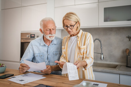 Serious angry senior couple calculate bills to pay domestic finances