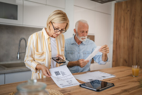 Mature woman do contact less payment and senior man read invoice