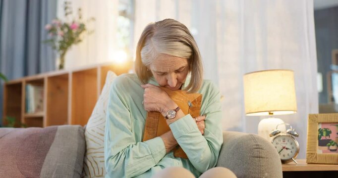 Senior, woman and sad with photograph on couch for reminiscing, nostalgia and remember memory of history or past. Elderly person, hug and thinking on sofa with picture, missing and mourning in home.
