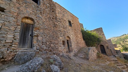 Captivating scene from Anavatos on Chios Island, Greece, featuring unique stone houses and a tree emerging amidst the historic architecture.