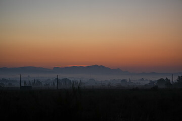 dawns behind the mountain with fog at its feet