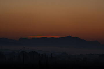 dawns behind the mountain with fog at its feet