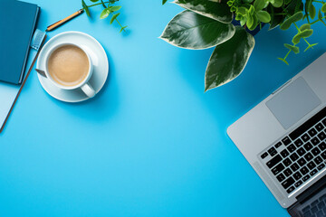 Top view of office desk with laptop, coffee cup and notebook on blue background for work online concept. Flat lay, top view, of desk space. High quality, in the style of work space.