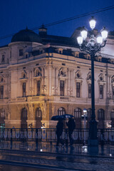 Naklejka premium Bilbao City at night with people with umbrellas