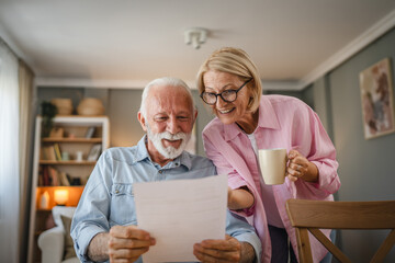 Senior man read a letter document whit mature woman who drink coffee