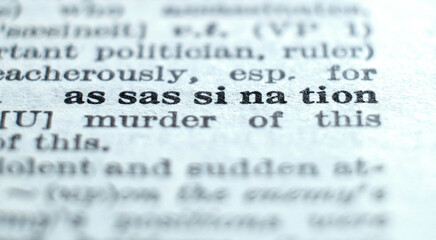 Fototapeta premium Assassination definition in the dictionary close-up, shallow depth of field and low-angle view. Murder of an important person or politician concept.