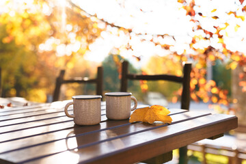 Autumn picnic at nature. Camping cups of coffee on wooden table in cozy forest. Calming drinks in...
