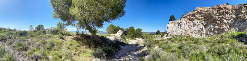 Panoramic view of a path with trees and bushes up the hill in the urban area of Igualada near Barcelona, Spain